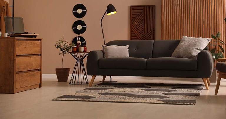 Moody living room with light wood floors, charcoal grey couch and records on the wall