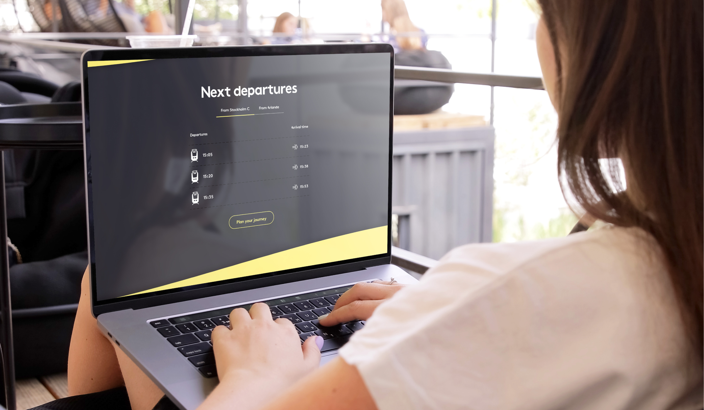 Person using a laptop displaying a travel webpage with next train departures from Stockholm C and Arlanda.