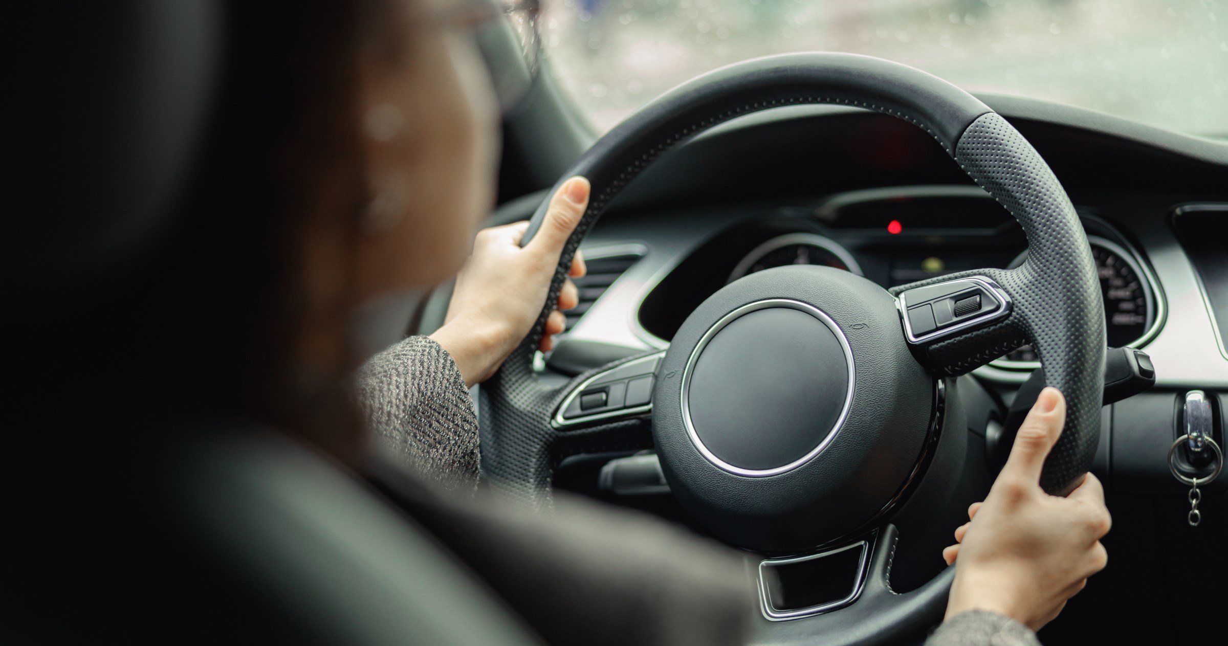 A nondescript view of a car steering wheel and dashboard. 