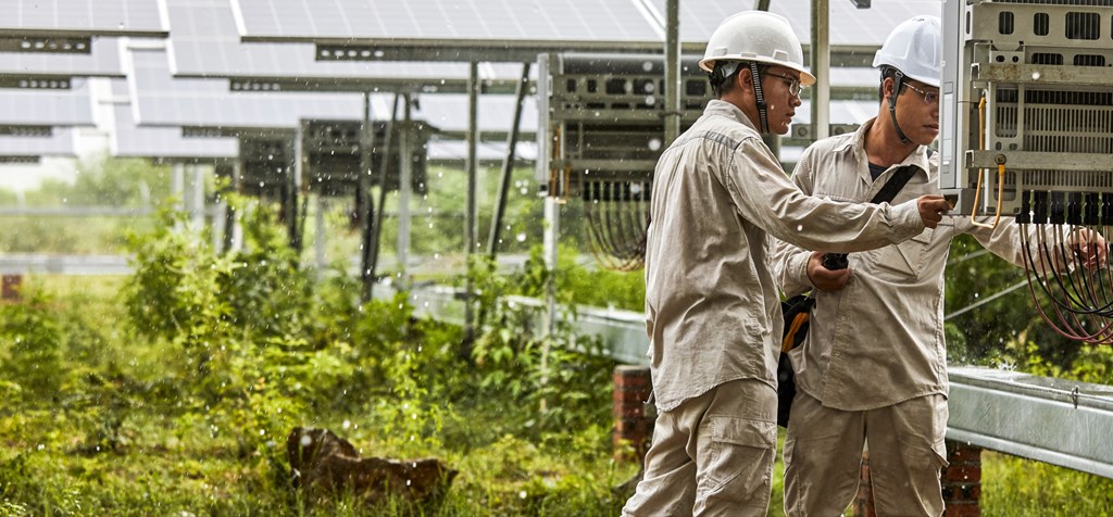 two technicians inspecting solar panels in the rain