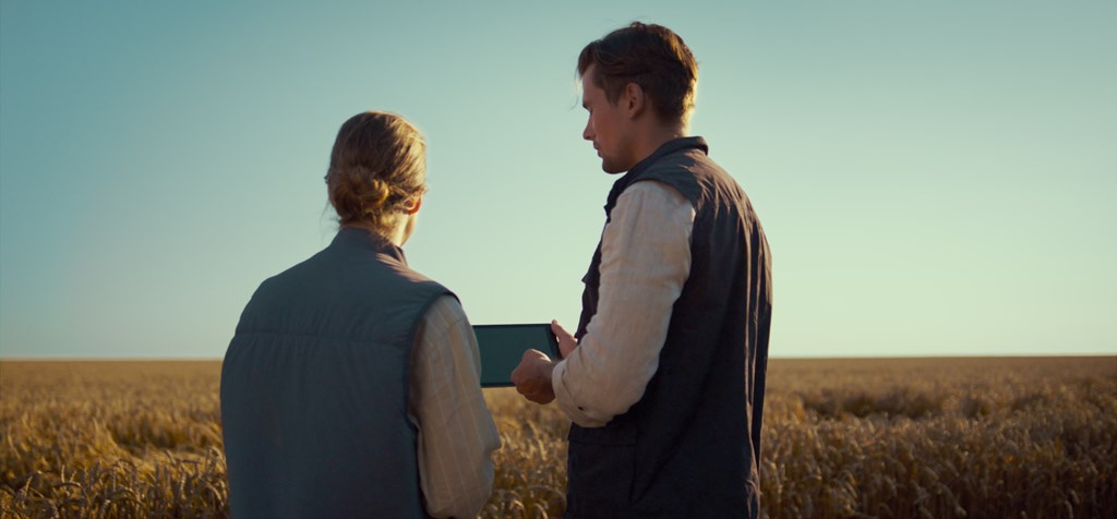 two farmers in a wheat field, one holding a tablet