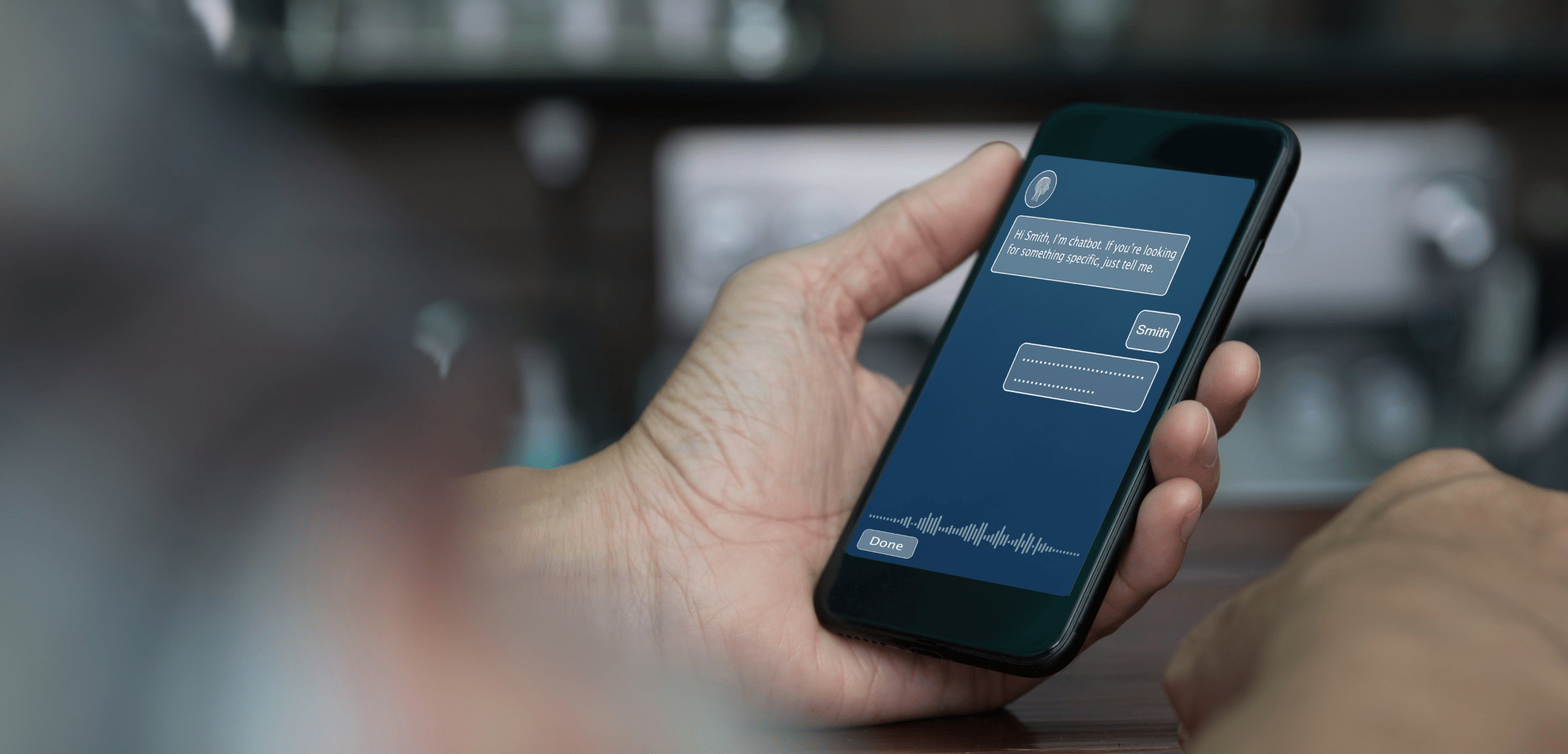 A person holds a smartphone displaying a chatbot conversation on the screen. The chatbot interface is shown with a message that reads, “Hi Smith, I’m a chatbot. If you’re looking for something specific, just tell me.” The conversation takes place in a minimalist, dark-themed interface with text bubbles and a voice input option at the bottom. The background is blurred, keeping the focus on the phone and the chatbot interaction, conveying a sense of modern technology and user engagement.