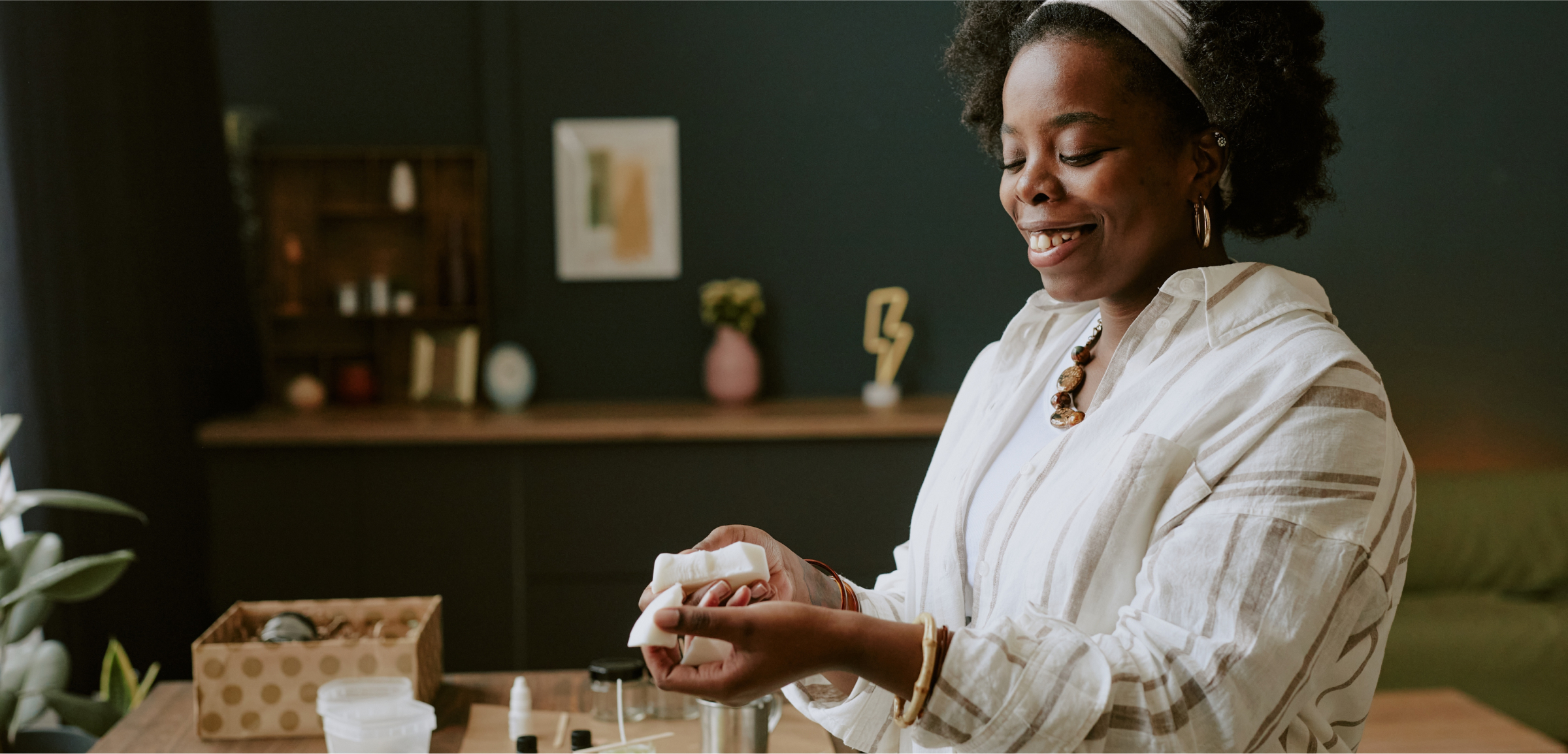  A woman is smiling as she works on making a candle. 