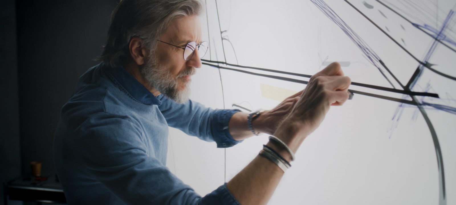 Experienced designer drawing on a whiteboard, conceptualizing innovative design ideas.