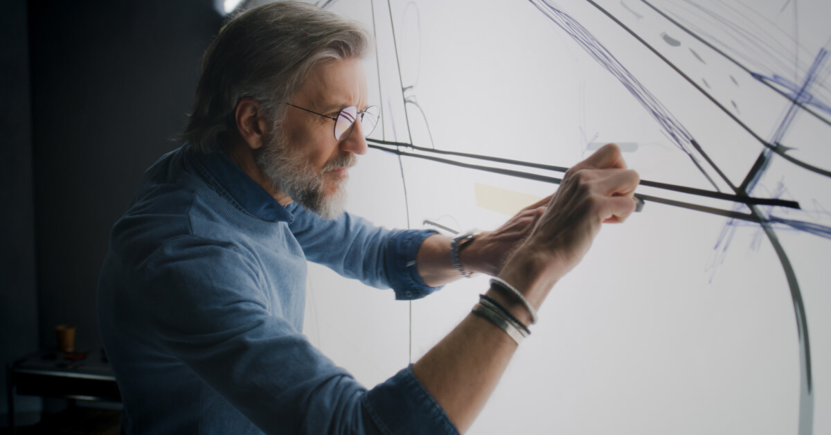 Experienced designer drawing on a whiteboard, conceptualizing innovative design ideas.