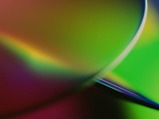 An abstract image featuring a smooth blend of vibrant colors, including green, yellow, purple, and red. The colors transition seamlessly, creating a gradient effect with soft, curved lines. The design has a dynamic, fluid feel, evoking a sense of motion and energy. The image is visually striking, with a modern and futuristic aesthetic, suitable for representing innovation or creative concepts.