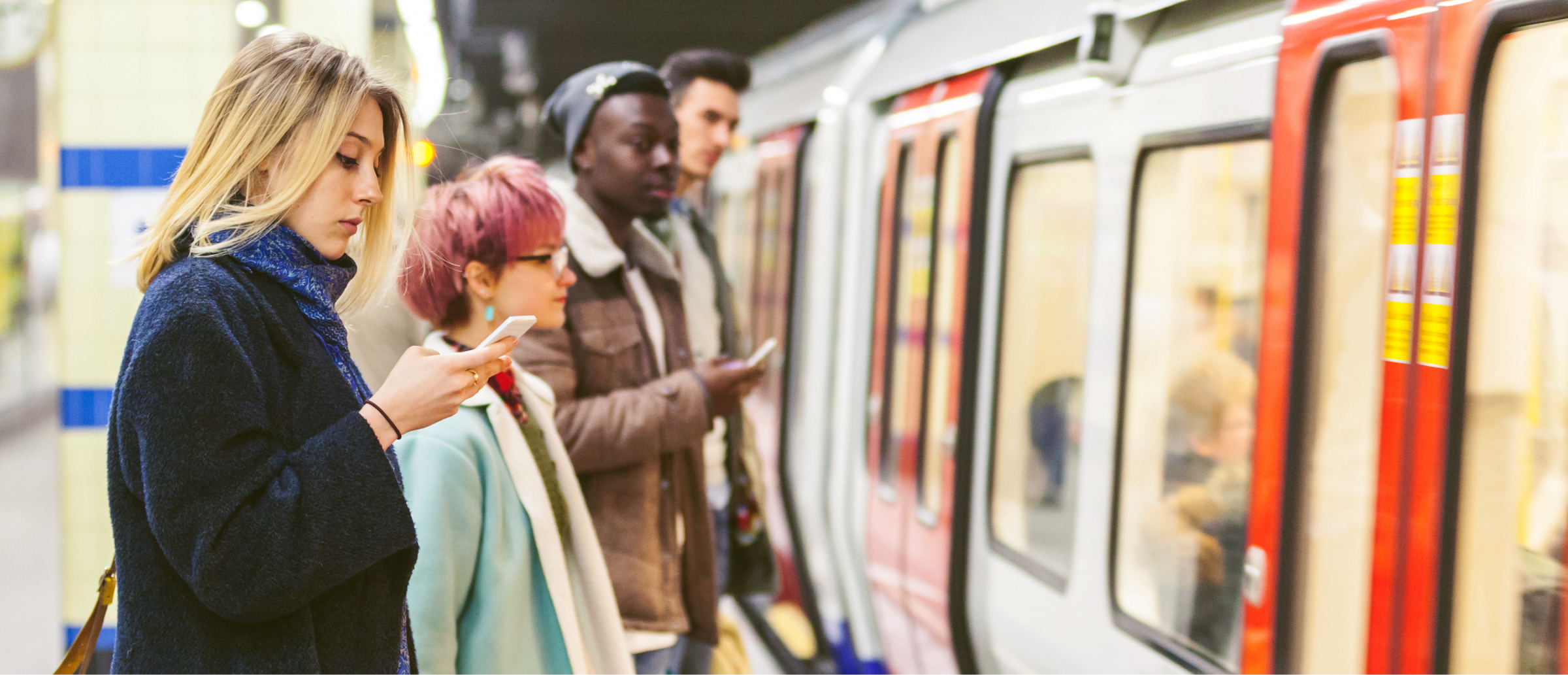 A group of commuters standing on a subway platform, all looking at their phones while waiting for a train. The train doors are open, and the commuters are lined up, preparing to board. The scene captures the routine of public transportation and digital engagement."