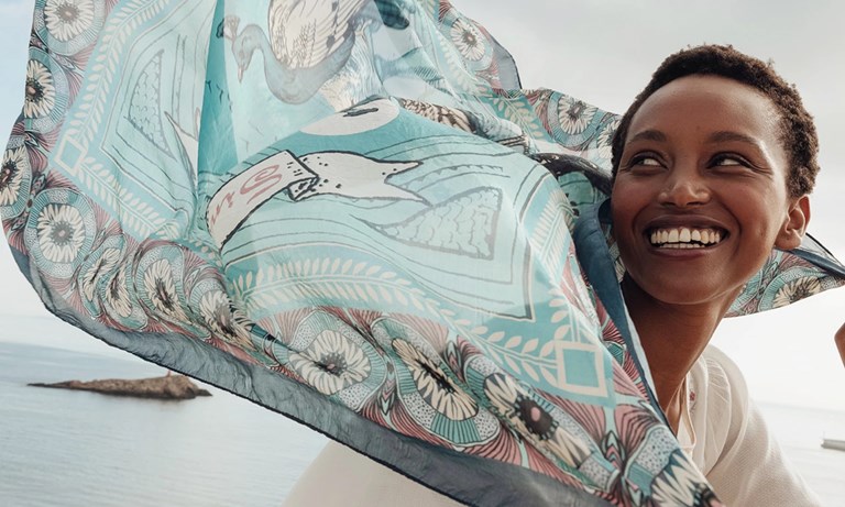 Woman smiling with green scarf blowing in the wind