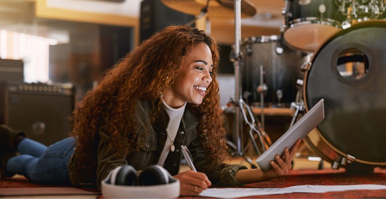 A person working at a desk with two monitors displaying data and code. The desk is neatly arranged with a laptop, notepad, and a cup of coffee. The workspace is well-lit, with a plant and a clean, modern aesthetic, emphasizing a productive work environment.