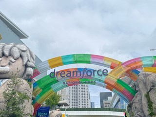 Colorful arches at the entrance of Dreamforce 2024 National Park, with a large stone statue and vibrant decorations set against a cityscape backdrop.