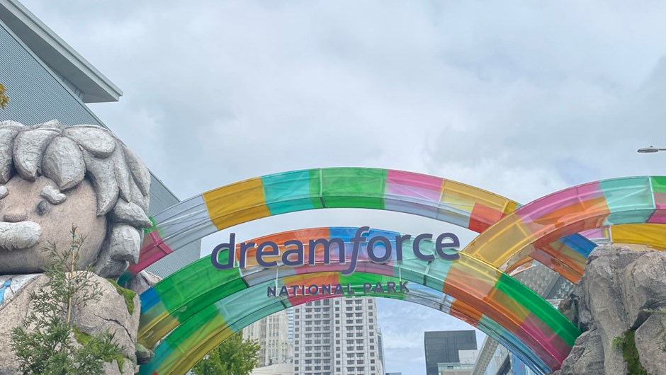 Colorful arches at the entrance of Dreamforce 2024 National Park, with a large stone statue and vibrant decorations set against a cityscape backdrop.