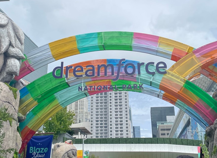Colorful arches at the entrance of Dreamforce 2024 National Park, with a large stone statue and vibrant decorations set against a cityscape backdrop.